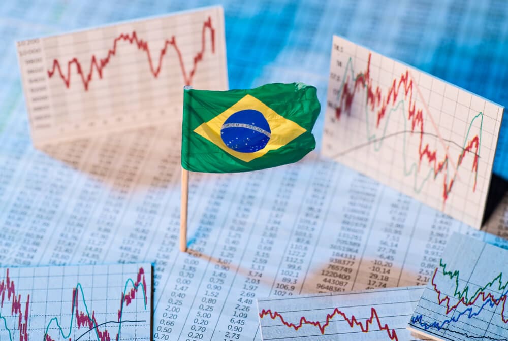 bandeira do Brasil ao centro e ao fundo tabelas com números de desenvolvimento financeiro, conceito financeiro para explicar o a popularização das criptomoedas no brasil